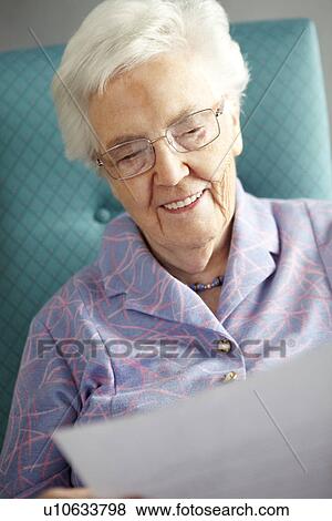 Stock Photo - Senior Woman Relaxing In Chair Reading Letter. Fotosearch