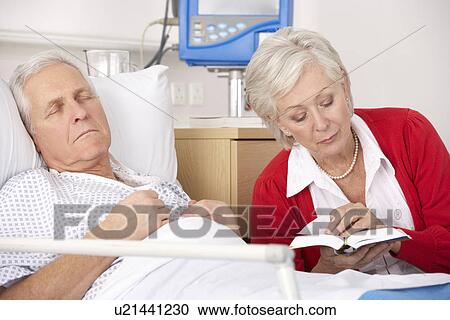 Stock Image - Senior woman visiting husband in hospital. Fotosearch