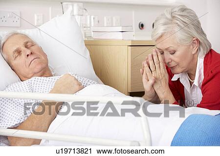 Stock Image - Senior woman with seriously ill husband in hospital. Fotosearch
