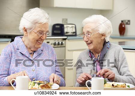 Picture - Senior women enjoying meal together at home. Fotosearch