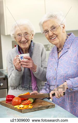 Stock Image - Senior women preparing meal together. Fotosearch