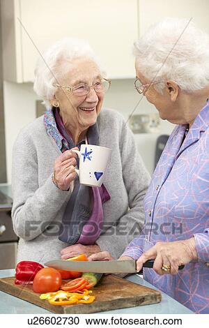 Stock Image - Senior women preparing meal together. Fotosearch