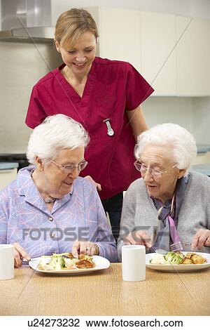 Senior women with carer enjoying meal at home View Large Photo Image Stock Image - Senior women with carer enjoying meal at home. Fotosearch