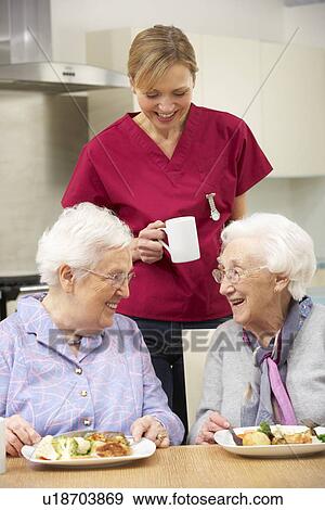 Stock Photo - Senior women with carer enjoying meal at home. Fotosearch