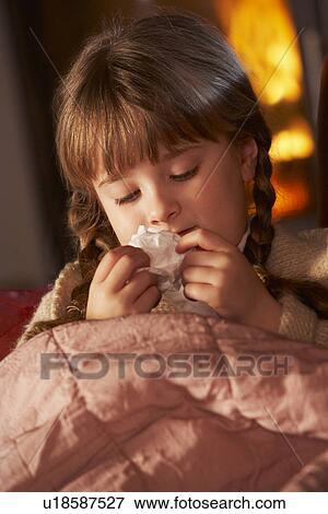 Stock Photo - Sick Girl With Cold Resting On Sofa By Cosy Log Fire. Fotosearch