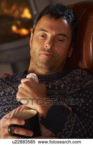 Sick Man With Cold Resting On Sofa By Cosy Log Fire View Large Photo Image Stock Photography - Sick Man With Cold Resting On Sofa By Cosy Log Fire. Fotosearch