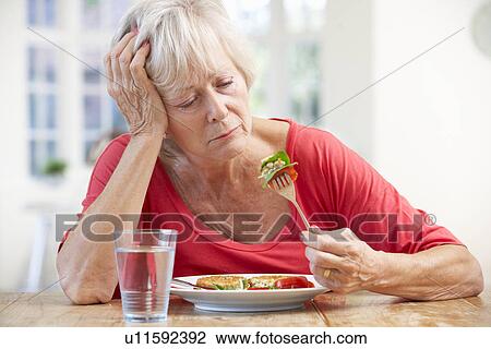 Stock Image - Sick older woman trying to eat. Fotosearch