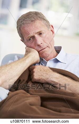 Stock Image - Sick, unhappy older man at home. Fotosearch