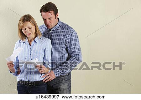 Stock Photo - Studio Shot Of Middle Aged Couple Looking at Bills. Fotosearch