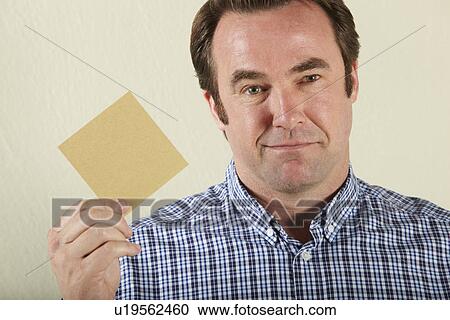 Stock Image - Studio Shot Of Middle Aged Man Holding Wage Packet. Fotosearch