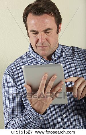 Stock Photo - Studio Shot Of Middle Aged Man Using Tablet Computer. Fotosearch