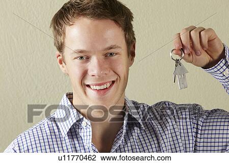 Stock Image - Studio Shot Of Young Man Holding Keys To First Home. Fotosearch