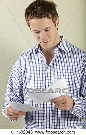 Studio Shot Of Young Man Looking at Bills View Large Photo Image Stock Image - Studio Shot Of Young Man Looking at Bills. Fotosearch