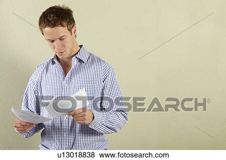 Studio Shot Of Young Man Looking at Bills View Large Photo Image Stock Photo - Studio Shot Of Young Man Looking at Bills. Fotosearch