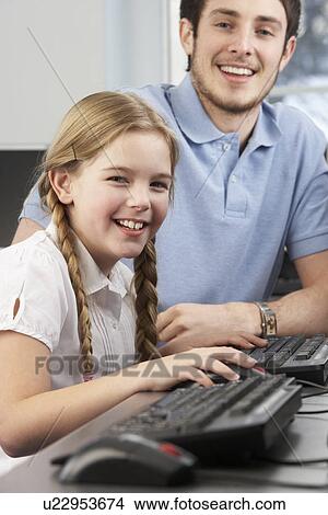 Picture - Teacher helping girl using computer in class. Fotosearch
