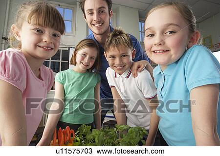 Stock Image - Teacher with children learning about plants. Fotosearch