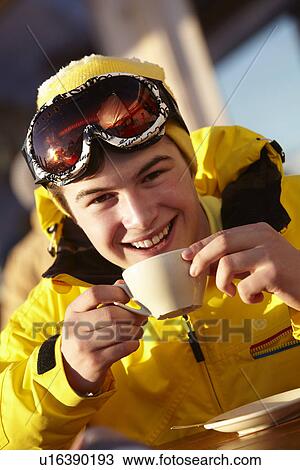 Stock Image - Teenage Boy Enjoying Hot Drink In CafÃ© At Ski Resort. Fotosearch