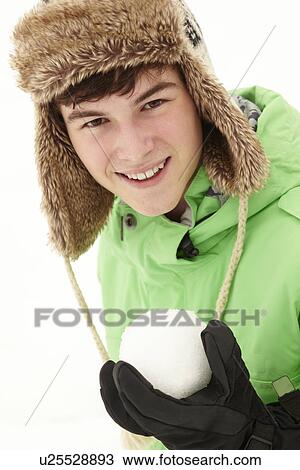 Stock Image - Teenage Boy Holding Snowball Wearing Fur Hat. Fotosearch