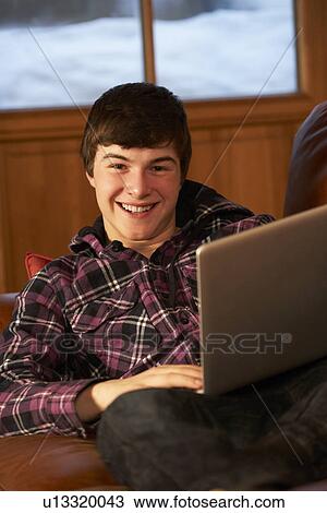 Stock Image - Teenage Boy Relaxing On Sofa With Laptop. Fotosearch