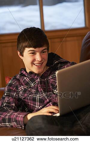 Stock Image - Teenage Boy Relaxing On Sofa With Laptop. Fotosearch