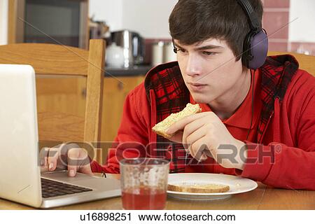 Teenage Boy Using Laptop Whilst Eating Breakfast View Large Photo Image Stock Image - Teenage Boy Using Laptop Whilst Eating Breakfast. Fotosearch