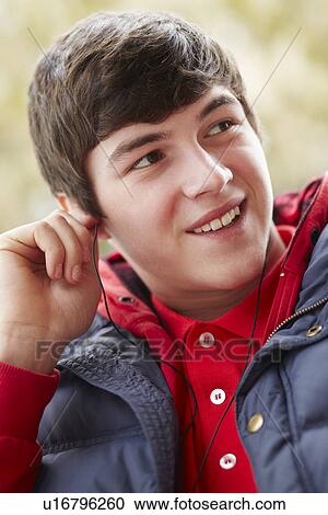 Stock Image - Teenage Boy Wearing Earphones And Listening To Music Wearing Winter Clothes. Fotosearch