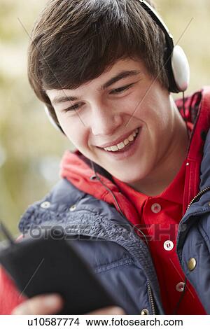 Picture - Teenage Boy Wearing Headphones And Listening To Music Wearing Winter Clothes. Fotosearch