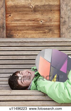 Teenage Boy With Snowboard On Ski Holiday Lying On Wooden Bench View Large Photo Image Stock Image - Teenage Boy With Snowboard On Ski Holiday Lying On Wooden Bench. Fotosearch