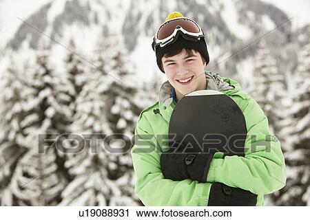 Stock Image - Teenage Boy With Snowboard On Ski Holiday In Mountains. Fotosearch