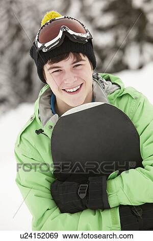 Stock Photo - Teenage Boy With Snowboard On Ski Holiday In Mountains. Fotosearch