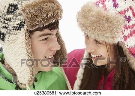 Stock Image - Teenage Couple In Snow Wearing Fur Hats. Fotosearch