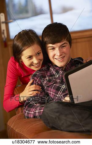 Teenage Couple Relaxing On Sofa With Tablet Computer View Large Photo Image Stock Photo - Teenage Couple Relaxing On Sofa With Tablet Computer. Fotosearch