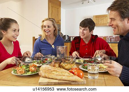 Stock Image - Teenage Family Eating Lunch Together In Kitchen. Fotosearch