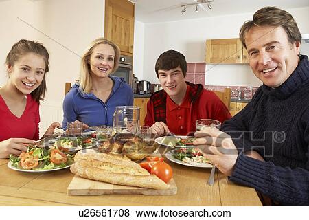 Stock Photo - Teenage Family Eating Lunch Together In Kitchen. Fotosearch