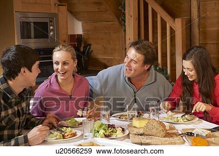 Stock Photo - Teenage Family Enjoying Meal In Alpine Chalet Together. Fotosearch