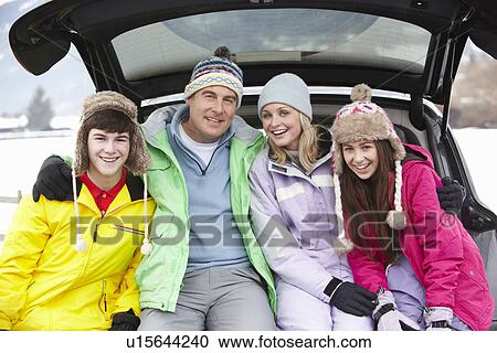 Stock Image - Teenage Family Sitting In Boot Of Car Wearing Winter Clothes. Fotosearch