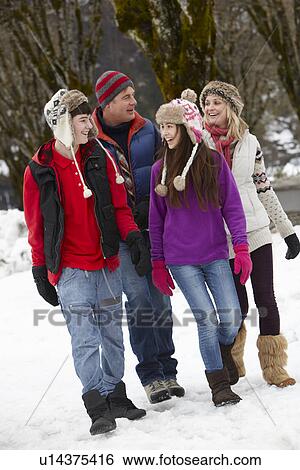 Stock Photograph - Teenage Family Walking Along Snowy Street In Ski Resort. Fotosearch