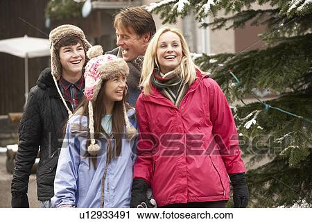Stock Image - Teenage Family Walking Along Snowy Town Street In Ski Resort. Fotosearch