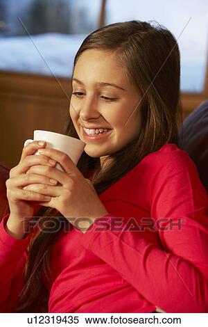 Stock Photography - Teenage Girl Relaxing On Sofa With Hot Drink. Fotosearch