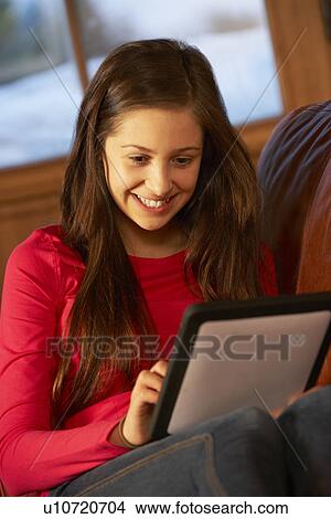 Picture - Teenage Girl Relaxing On Sofa With Tablet Computer. Fotosearch