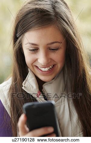 Stock Photo - Teenage Girl Texting On Smartphone Wearing Winter Clothes. Fotosearch