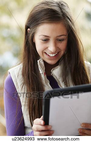Stock Image - Teenage Girl Using Tablet Computer Outdoors Wearing Winter Clothes. Fotosearch