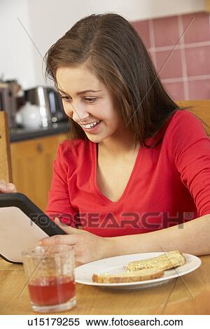 Teenage Girl Using Tablet Computer Whilst Eating Breakfast View Large Photo Image Stock Photography - Teenage Girl Using Tablet Computer Whilst Eating Breakfast. Fotosearch