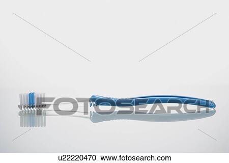 Stock Image - Toothbrush lying on glass shelf. Fotosearch
