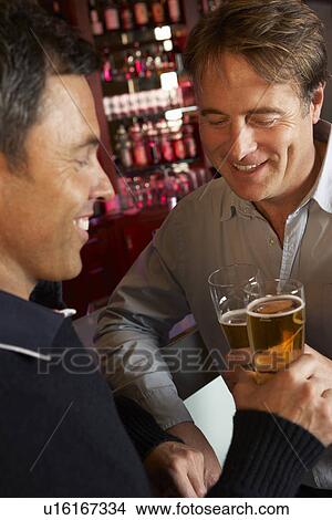 Picture - Two Men Enjoying Drink Together In Bar. Fotosearch