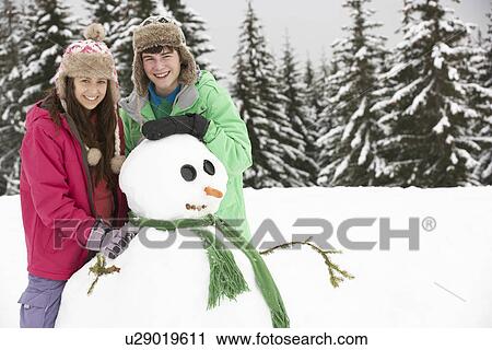 Two Teenagers Building Snowman On Ski Holiday In Mountains View Large Photo Image Stock Image - Two Teenagers Building Snowman On Ski Holiday In Mountains. Fotosearch