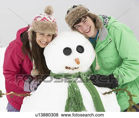 Two Teenagers Building Snowman On Ski Holiday In Mountains View Large Photo Image Stock Photo - Two Teenagers Building Snowman On Ski Holiday In Mountains. Fotosearch