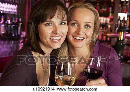 Picture - Two Women Enjoying Drink Together In Bar. Fotosearch
