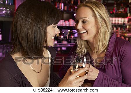 Stock Image - Two Women Enjoying Drink Together In Bar. Fotosearch