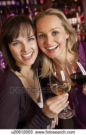 Stock Image - Two Women Enjoying Drink Together In Bar. Fotosearch